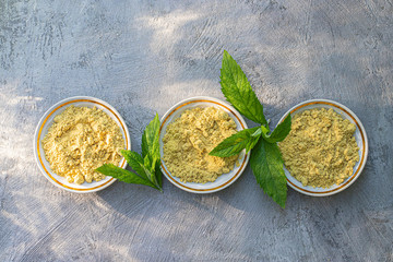 Mustard in saucers with mint leaves on a gray background. Seasoning for dishes