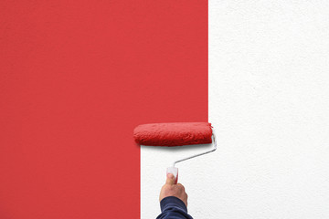 hand holds paint roller and painting a wall 