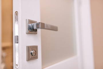 Part of the metal handle on a modern interior door with a lock provides better protection for the apartment.