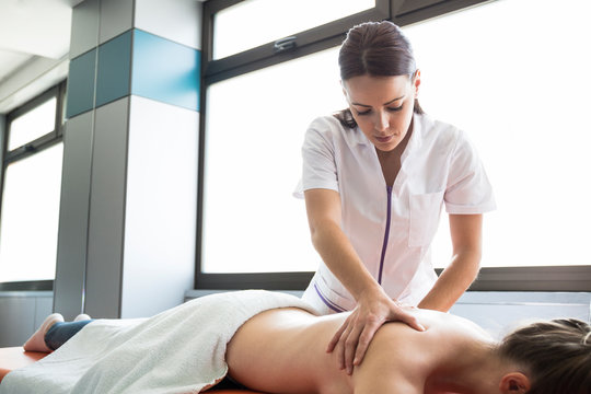 Female physiotherapist massaging the back of a woman