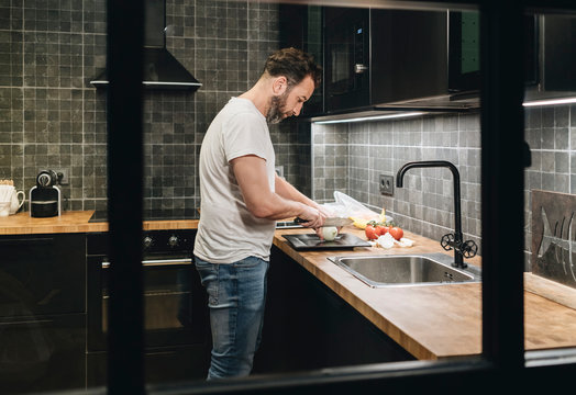 Mature man standing in kitchen, chopping onions