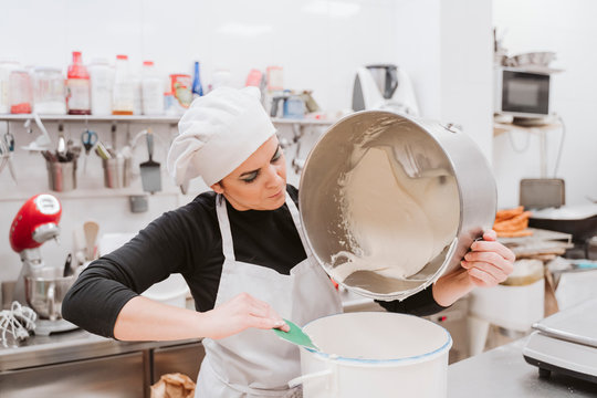 Female baker emptying batter in container at bakery