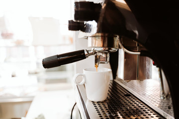 Coffee being poured in cup from machine in bakery