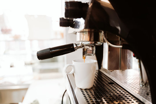 Coffee being poured in cup from machine in bakery