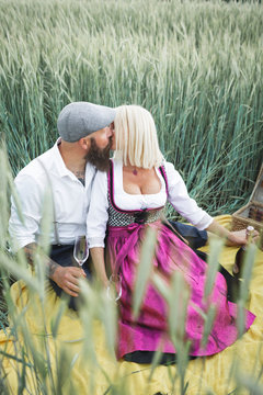 Mature couple holding champagne glasses kissing while sitting amidst plants on land