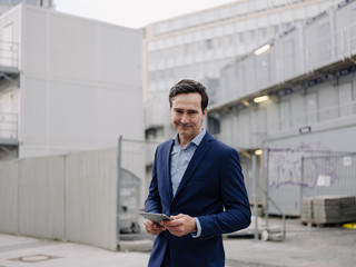 Portrait of a confident mature businessman with tablet at a construction site