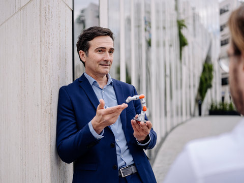 Mature businessman showing robot arm to colleague in the city