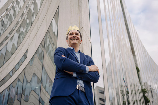 Happy mature businessman wearing a toy crown in the city