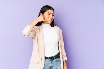 Young indian woman isolated on purple background showing a mobile phone call gesture with fingers.