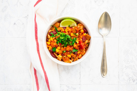 Bowl of vegetarian chili with tofu, corn, kidney and pinto beans, cilantro and lime