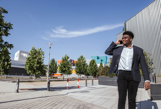 Male professional talking over smart phone while standing in city during sunny day