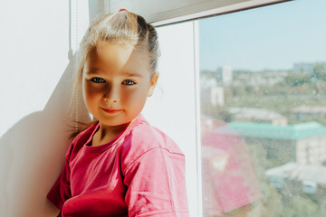 portrait of a  little child girl at home by the window on a sunny day.  