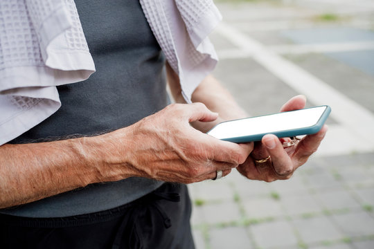 Close-up of senior man using mobile phone while standing outdoors