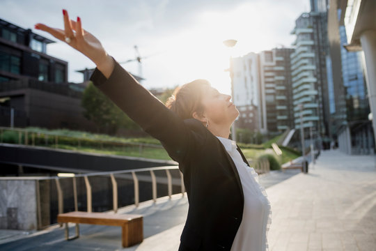 Businesswoman with arms raised standing on footpath in city