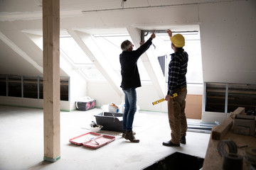 Architect and construction worker discussing about window frame in renovating house