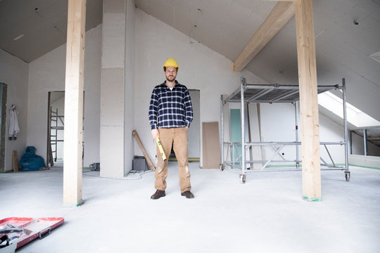 Confident construction worker standing at renovating home