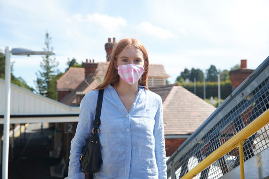 Young woman wearing protective face mask at railroad station