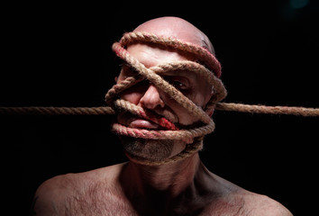 Photo of binded adult man with rope on face