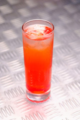 Red refreshing summer cocktail with ice in a glass.