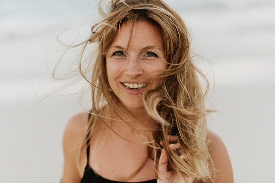 Close-up of happy woman with tousled hair against sea