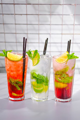 Three refreshing summer cocktails in glasses with tubes on the bar rack.