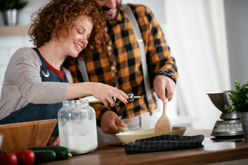 Boyfriend and girlfriend making delicious food at home. Loving couple cooking in kitchen.