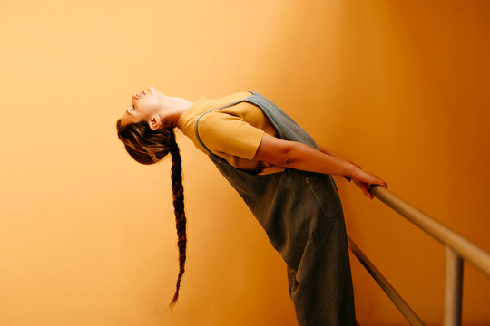Young woman bending backwards in front of orange wall