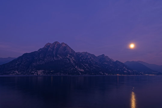 Italy, Lombardy, Riva di Solto, Lake Iseo and Corna Trentapassi mountain at night with full moon