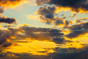 A very dramatic sky full of yellows, blues and oranges. Contrasting clouds during sunset illuminated by the setting sun. Bright saturated natural background. High quality photo