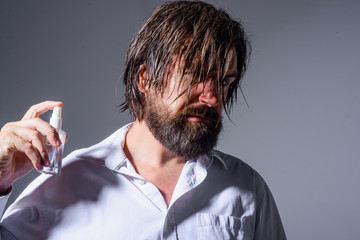 Handsome bearded man with bottle of perfume. Cosmetics advertising. Male perfume, fragrance, cosmetics. Bearded man in leather jacket. Bottle of perfume.