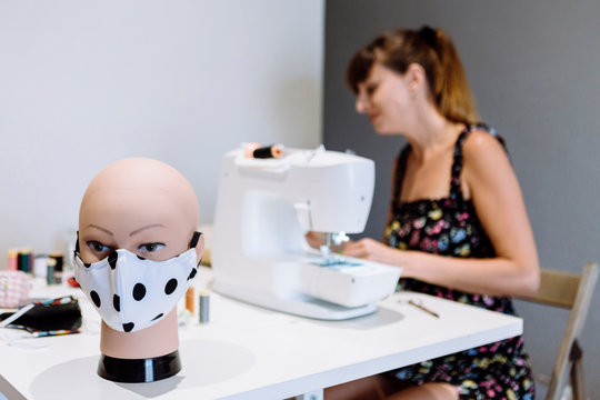 Close-up of mannequin with mask on table while female tailor working in background