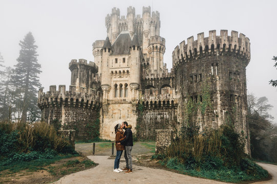 Couple kissing while standing against Butron Castle, Basque Country, Spain