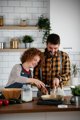 Boyfriend and girlfriend making delicious food at home. Loving couple cooking in kitchen.