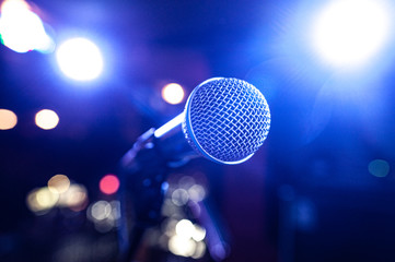 round microphone in the rays of multi-colored lamps on the concert stage