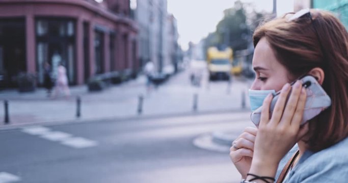 Sick Woman Wearing A Protective Mask Sneezing, Walking In The City, Talking on Smartphone. SLOW MOTION, Gimbal Stabilizer. Young Female in face mask against air pollution and coronavirus Covid-19. 