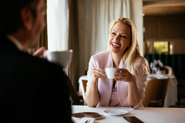Beautiful businesswoman dressed in the suit drinking coffee. Businessman and businesswoman enjoying in the restaurant.