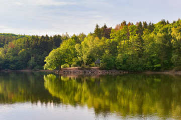 Lake in spring with green trees on the shore at sunrise