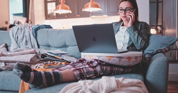 Young Business Woman Working From Home, Dog Interrupts. SLOW MOTION. Conference call on laptop. Female learning online. Puppy playing with work papers. Mess in a room. Entrepreneur Work life balance. 