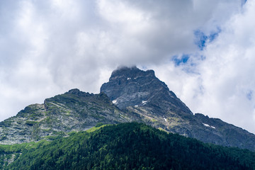 Beautiful mountain landscape in summertime. Mighty mountains with snow in cloudy weather.