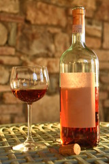 Weinglas und Flasche auf einem Tisch vor Bruchsteinmauer im Chianti