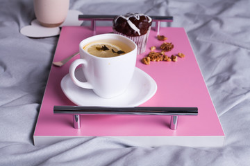 Close up of tasty and delicious breakfast in bed with cake and cacao. Fresh bake and coffee on pink wooden board. Concept of autumn morning.