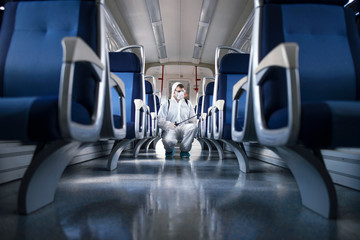 Public transportation healthcare. Man in white protection suit disinfecting and sanitizing subway...