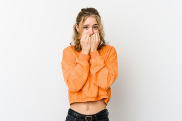 Young caucasian woman on white backrgound biting fingernails, nervous and very anxious.