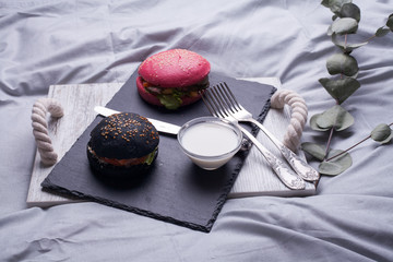 Colorful too mini burgers served on black plate as appetizer. Delicious classic, black and pink...