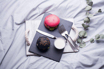 Colorful too mini burgers served on black plate as appetizer. Delicious classic, black and pink slider burgers loaded with beef patty, crispy chicken, lettuce, coleslaw, cheese, mushrooms. Image