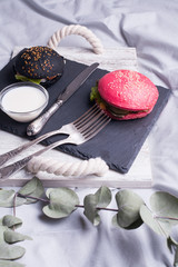 Colorful too mini burgers served on black plate as appetizer. Delicious classic, black and pink...