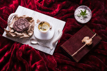 good morning - breakfast with sweet bun and tea on wooden tray and flowers in bed
