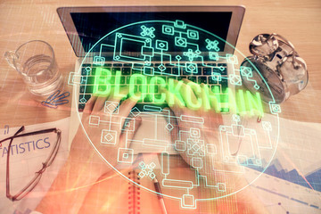 Double exposure of man's hands typing over computer keyboard and crypto currency theme hologram...