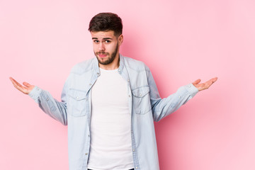 Young caucasian business man posing in a white background isolated doubting and shrugging shoulders...