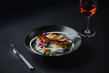 a delicious lunch in a luxury restaurant served in a black plate with a glass of fine wine